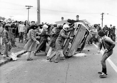 Rioters overturn a car during a demonstration outside Eden Park