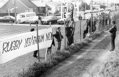 Anti-tour protesters demonstrate behind a barbed wire fence