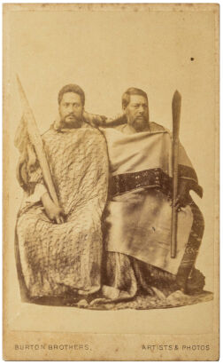 AMERICAN PHOTOGRAPHIC COMPANY / BURTON BROS, AUCKLAND Two Māori men seated in cloaks holding taiaha