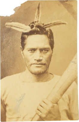 UNKNOWN PHOTOGRAPHER Portrait of a Māori man with 3 feathers, collarless shirt, holding taiaha wearing a ring on his last finger