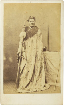 UNKNOWN PHOTOGRAPHER Portrait of a Māori man wearing a floor length Kaitaka aronui and holding a taiaha