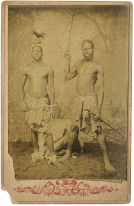 UNKNOWN PHOTOGRAPHER Southern African men, one with feather headdress the other with spear wearing printed cotton wrappers