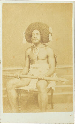 MONTAGU SCOTT, LEVUKA Portrait of Fijian Kai colo mountain warrior with Boar's tusk necklace and hair adornment seated on Victorian chair