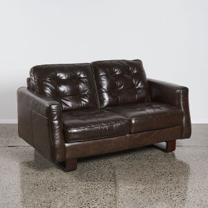 A Dark Brown Two-Seater Leather Couch With Wooden Sleigh Base