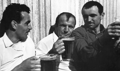 JAMES L. ANDERSON Manapouri, New Zealand. Three Yugoslav contract workers drinking outside the bar at West Arm camp.