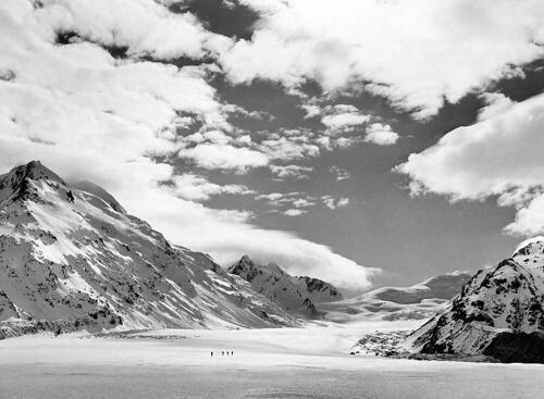 UNKNOWN PHOTOGRAPHER Mt. Cook. Ski-tourers gradually dissapear from sight on the vast acres of ice and snow of the Tasman Glacier.