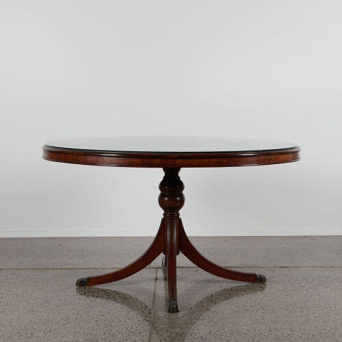 A Circular Mahogany Table With A Glass Overlay