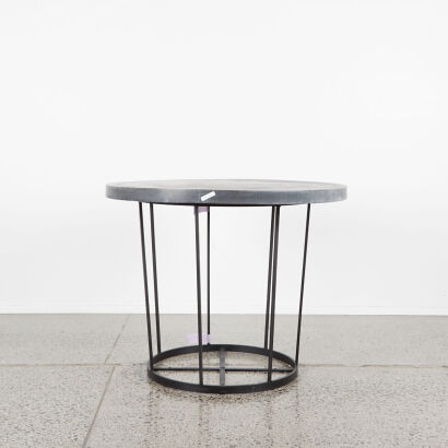 A Rustic Circular Table With Black Metal Base And Cast Grey Top