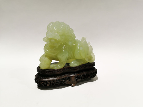 A Chinese Light Green Jade Carving of Lion Dog with Wooden Base