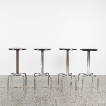 A Set Of Four Minimalist Barstools With Stainless Base And Black Seat