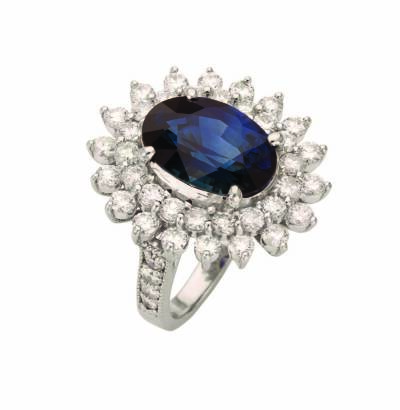 A sapphire and diamond ring, the oval sapphire of estimated weight 6.92 carats in a four claw setting surrounded by a double border of claw set round brilliant diamonds of estimated weight 2.43 carats. Platinum. Weight 14.5 grams. Size L 1/2.