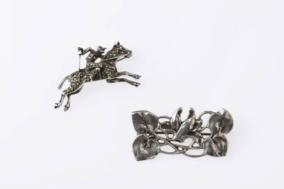 Two silver brooches 1905 - 1935. One, unmarked silver cast and pierced honesty plants in the Art Nouveau manner and the other silver and marcasite galloping horse with rider. Lengths 46mm - 42mm. Circa 1905 - 1935.