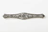 An Art Deco diamond brooch, eleven early brilliant cut diamonds set in a long pierced open work brooch with millgrain edge. Weight 7.0 grams. Length 69mm. Circa 1925.&nbsp;