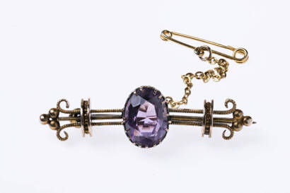 An Edwardian amethyst bar brooch the oval amethyst measuring 10mm x 8mm claw set in a triple bar design mount. Circa 1910. Yellow gold. Weight 4.53 grams. 