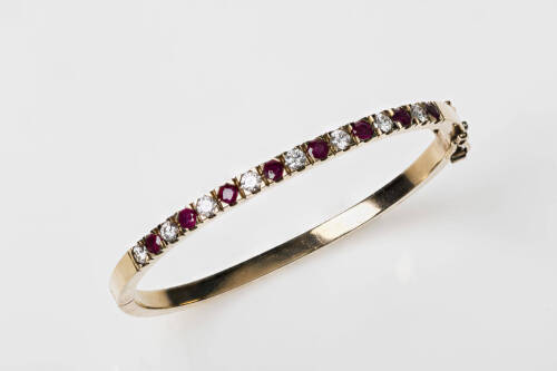 A ruby and diamond bangle, the front section set with eight round rubies of total estimated weight 1.12 carats and eight round brilliant cut diamonds of total estimated weight 0.83 carat. 9ct yellow gold. Weight 16.3 grams. Inside diameter 5.5cm.