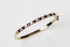 A ruby and diamond bangle, the front section set with eight round rubies of total estimated weight 1.12 carats and eight round brilliant cut diamonds of total estimated weight 0.83 carat. 9ct yellow gold. Weight 16.3 grams. Inside diameter 5.5cm.