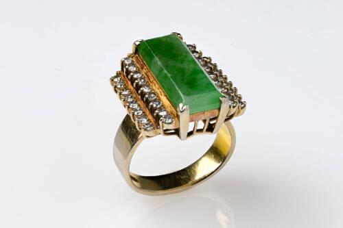 A jadeite and diamond ring, the centre jadeite measuring 20mm x 8mm, is four claw set between two single cut diamond set border rows. 18ct yellow gold. Weight 10 grams. Size K.&nbsp;&nbsp;