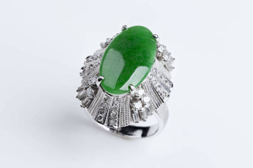 A jade and diamond ring, the oval jade measuring 18mm x 10mm surrounded by baguette and brilliant cut diamonds. 18ct white gold. Weight 10.21gms. Size K.