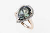 A tanzanite and diamond ring, three claw set with a pear-shaped tanzanite of known weight 6.18 carats in a diamond set frame. Known total diamond weight 0.26 carat. 18ct rose gold. Weight 7.3 grams. Size N.