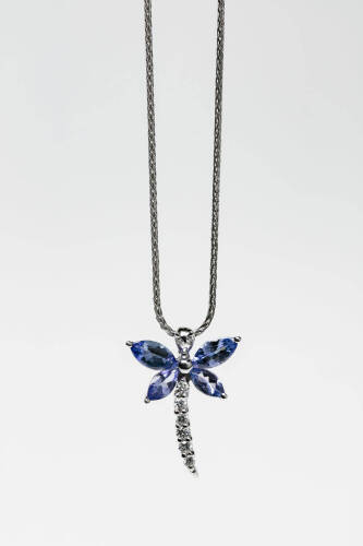 A tanzanite and diamond pendant, the four marquise shape tanzanite set with a diamond line in the shape of a dragonfly. 18ct white gold. Weight 2.68 grams. Length 40cm.