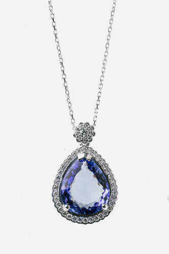 A tanzanite and diamond pendant, claw set with a pear-shaped tanzanite of known weight 7.73 carats, in a diamond set frame with diamond cluster surmount. Total diamond weight 0.26 carat. 18ct white gold. Weight 4.7 grams. Length 25mm.&nbsp;To be sold with a fi