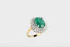 An emerald and diamond ring, the oval emerald measuring 13.6mm x 11.06mm of reported weight 6.65 carats, surrounded by double row of round brilliant cut diamonds of reported total weight 1.28 carats.18ct yellow gold. Weight 11.98 grams. Size N.