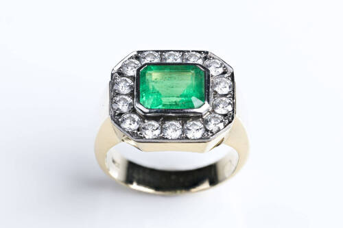An emerald and diamond ring, the emerald cut emerald of estimated weight &nbsp;3.25 carats surrounded by 14 brilliant cut diamonds of estimated weight 1.68 carats. 18ct white and yellow gold. Weight 14.5 grams. Size T.&nbsp;&nbsp;