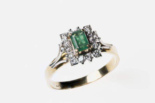An emerald and diamond cluster ring, the central emerald cut diamond ring in a round brilliant cut diamond set frame. 18ct yellow gold. Weight 4.7 grams. Size S.