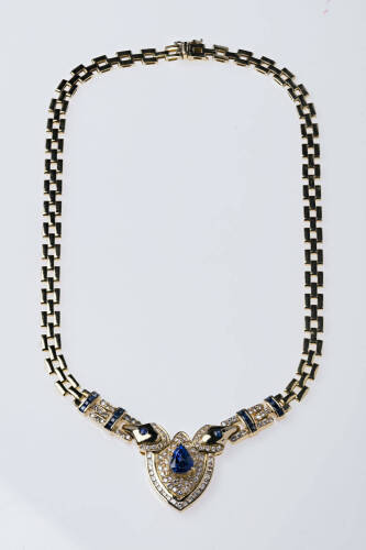 A sapphire and diamond necklace, the pear shaped sapphire of estimated weight 3.10 carats in a shield shaped centre mount with a surround of pave diamonds with two arms of open square diamond and sapphire set links. Estimated total diamond weight 1.90 car