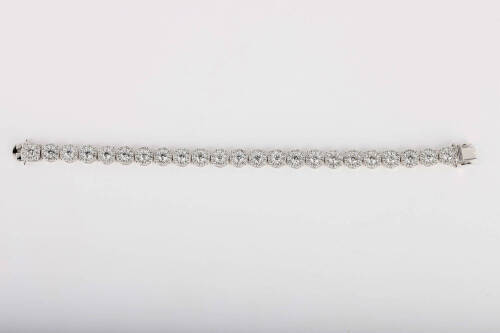A diamond bracelet, of articulated design, with twenty-three circular diamond cluster panels. Total known diamond weight 9 carats. 18ct white gold. Weight 22.1 grams. Length 17.5cm.