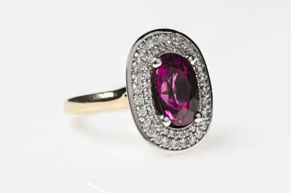 A rubellite and diamond ring. The oval rubellite 12mm x 8.8mm of estimated weight 4.74 carats surrounded by a double row of round brilliant diamonds bead set with a plain polished bezel of estimated weight 0.96 carats. 18ct white and yellow gold. Weight 1