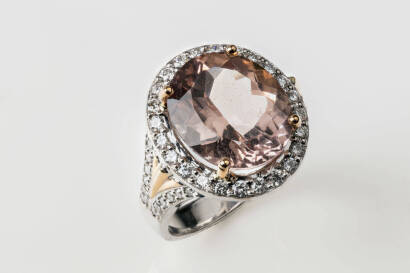 A morganite and diamond ring. The oval morganite 14.2mm x 12.12mm of estimated weight 7.69 carats surrounded by 24 claw set round brilliant diamonds of estimated weight 0.74 carats. 18ct white and rose gold. Weight 12.3 grams. Size N.&nbsp;