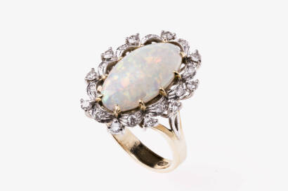 An opal and diamond ring, the 17mm x 10mm oval opal claw set with a foliate and 20 round brilliant diamond border. 18ct yellow gold. Weight 8.9 grams. Size P.&nbsp;