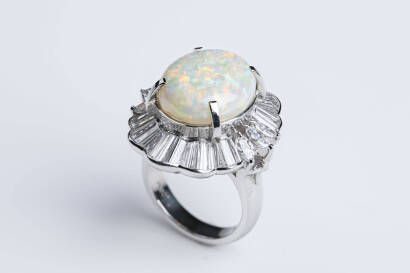 An opal and diamond ring, the oval opal of estimated weight 6.42 carats claw set in a scallop surround of marquise and baguette cut diamonds of estmated weight 2.24 carats. Platinum. Weight 17.4 grams. Size K.