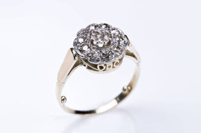 A diamond cluster ring, the centre old cut diamond surrounded by mixed cut diamonds to form a flower cluster claw and bead set in a scrolled basket mount. Weight 3.73 grams. Size M. Circa 1920.&nbsp;&nbsp;&nbsp;