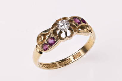 A Victorian ruby and diamond ring, the round brilliant cut diamond in a raised mount of scroll design with two round rubies on each side. 18ct yellow gold. Weight 2.7 grams. Size K. Registered number 312628. Circa 1895.&nbsp;&nbsp;