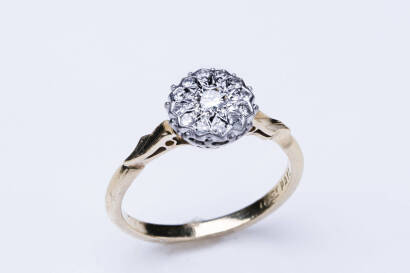 A diamond ring, of round cluster design illusion set with twelve single cut diamonds surrounding a centre old cut diamond of estimated weight 0.25 carat. &nbsp;18ct yellow gold and palladium. Weight 3.41 grams. Size N&frac12;.&nbsp;