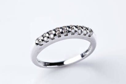 A diamond band ring, set with 18 small round brilliant cut diamonds of known weight 0.25 carat. 9ct white gold. Weight 2.33 grams. Size N.
