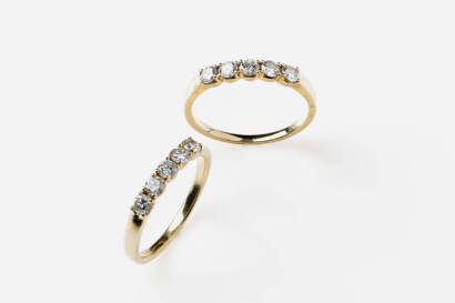 A pair of diamond rings, the ten round brilliant cut diamonds of estimate total weight 0.80 carats are claw set into two band rings.18ct yellow gold. Weight 5.09 grams. Size M.