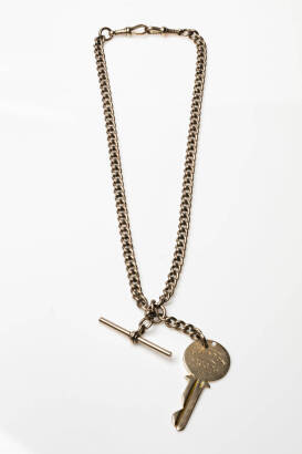 An Edwardian rose gold albert watch chain, curb link design, hung with a T-bar, swivels and a yellow gold key engraved H. E. HERRING, M.P., LEESTON 1937. 9ct rose and yellow gold. Weight 35.16 grams. Length 38.5cm.