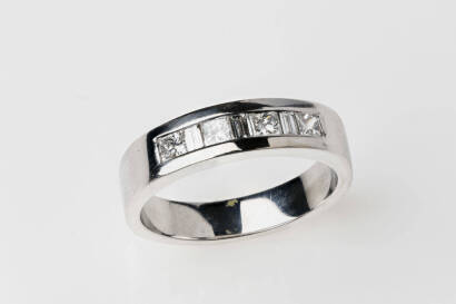 A diamond band ring, the four princess cut and three baguette diamonds of estimated total weight 0.62 carat are channel set across front of band. 18ct white gold. Weight 8.05 grams. Size R.