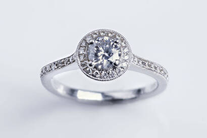 A diamond ring, the round brilliant diamond of estimated weight 0.47 carat, surrounded by a halo of diamonds and continuing down shoulder. Estimated total weight 0.75 carat. Platinum. Weight 4.36 grams. Size K&frac12;.