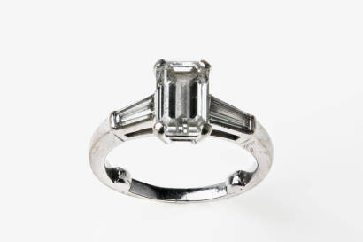 A 2 carat solitaire diamond ring, the emerald cut diamond of known weight 2.03 carats set either side with tapered baguette diamonds of known weight 0.58 carat. 18ct white gold. Weight 4.91 grams. Size H.