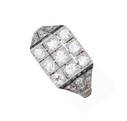 An Art Deco sapphire and diamond ring, circa 1920's. The square, pierced plaque set with nine old brilliant cut diamonds of estimated total diamond weight 0.75 carat, channel set calibre blue sapphires to tapered diamond set shoulders. Platinum. Weight 4.