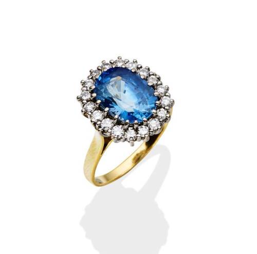 A sapphire and diamond cluster ring, the claw set oval blue sapphire of estimated weight 4.96 carats, surrounded by eighteen round brilliant cut diamonds of estimated weight 0.66 carat. 18ct yellow and white gold. Weight 5.66 grams. Size P &frac12;.