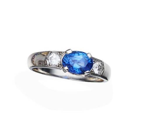 A sapphire and diamond ring, horizontally set with an oval blue sapphire of known weight 1.20 carats, shouldered by a .10 carat round brilliant cut diamond. Platinum. Weight 6.66 grams. Size N.