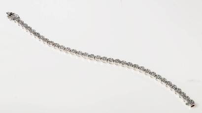 A diamond bracelet, two hundred and forty-five round brilliant cut diamonds of estimated weight 4.88 carats set in a line of thirty-five hinged rosette clusters.18ct white gold. Weight 14.21 grams. Length 180mm.