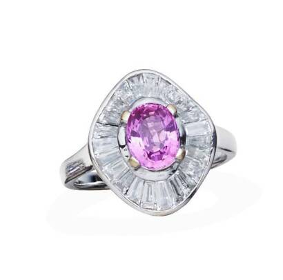 A sapphire and diamond ring, of ballerina design, four claw set with a central oval sapphire of estimated weight 1.46 carats, within an undulating border of tapered baguette diamonds. 18ct white gold. Weight 6.47 grams. Size P&frac12;.