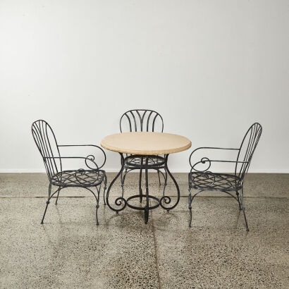 An Outdoor Round Concrete Top Table With Three Rought Iron Chairs