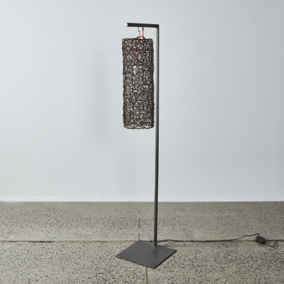 A Designer Floorstanding Lamp With Metal Base & Cane Weave Shade